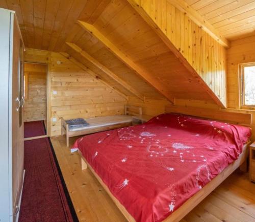 Una gran cama roja en una cabaña de troncos en Vikendica Kameno, en Kameno