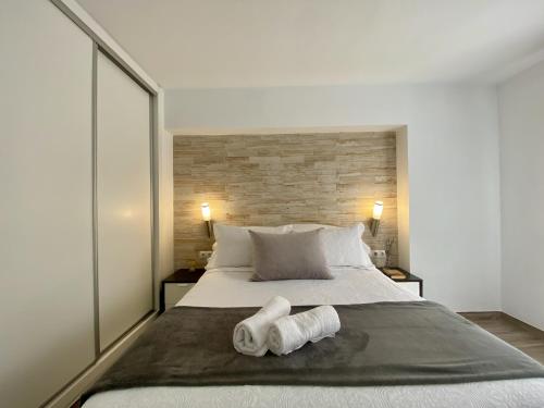 Apartamento Beli Málaga في بينالمادينا: غرفة نوم بسرير كبير عليها منشفتين