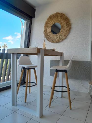 une table avec deux chaises et un miroir mural dans l'établissement Naturistecapdagde L'indigo, au Cap d'Agde