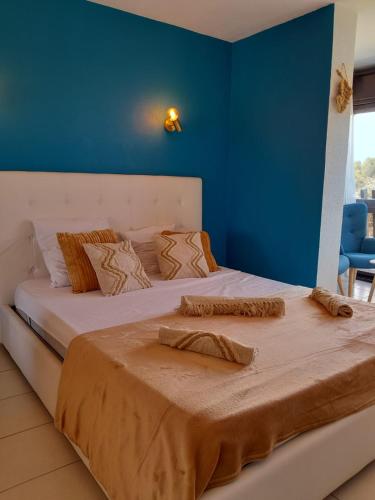une chambre avec un grand lit avec un mur bleu dans l'établissement Naturistecapdagde L'indigo, au Cap d'Agde