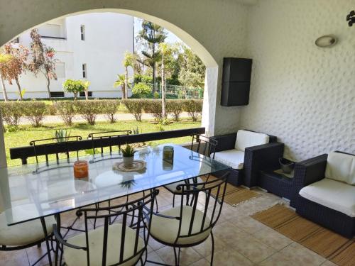 a dining room with a glass table and chairs at Chez Marya Asilah Marina Golf uniquement famille in Asilah