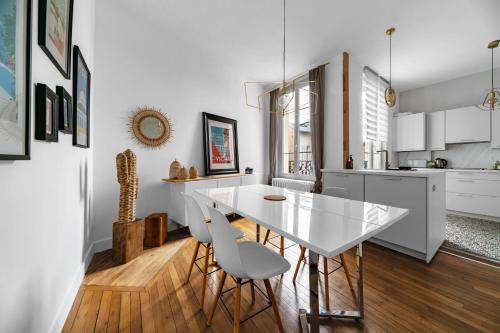 une cuisine et une salle à manger avec une table et des chaises blanches dans l'établissement Le Joffre - Appartement calme et lumineux en centre ville, à Vichy
