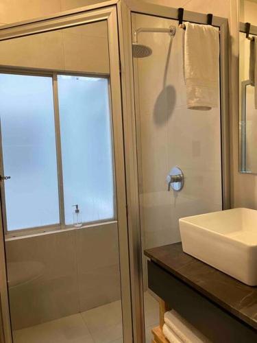 a bathroom with a sink and a glass shower at Coyoacan historico, museo Frida. in Mexico City