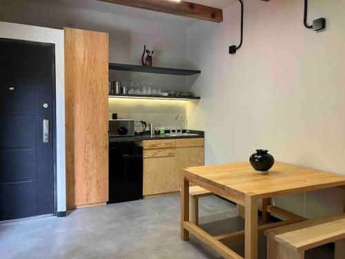a kitchen with a wooden table and a black refrigerator at Coyoacan historico, museo Frida. in Mexico City