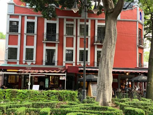 a red and white building with a tree in front of it at Coyoacan historico, museo Frida. in Mexico City