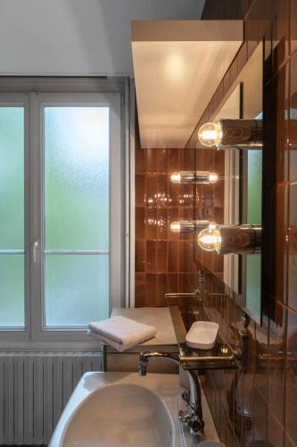 La salle de bains est pourvue d'un lavabo, d'une fenêtre et d'un miroir. dans l'établissement Le Joffre - Appartement calme et lumineux en centre ville, à Vichy