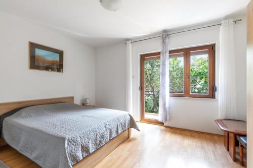 a white bedroom with a bed and a window at Apartman Marco Polo in Selce