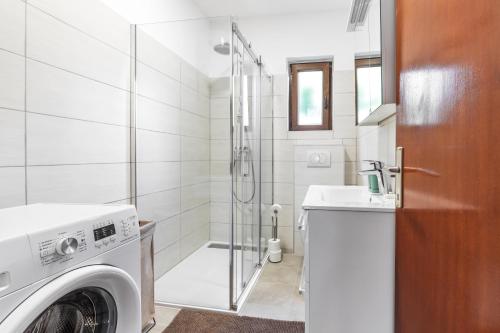 a washing machine in a bathroom with a shower at Apartman Marco Polo in Selce