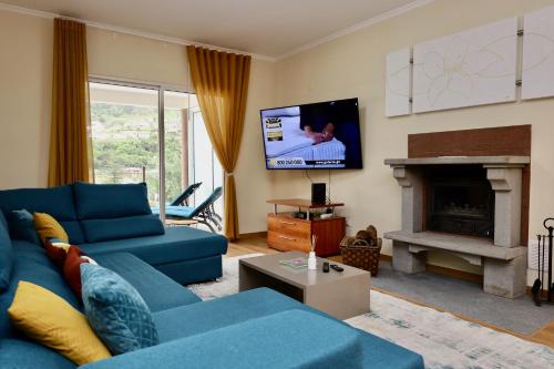 a living room with a blue couch and a tv at Quinta dos Cardais by AnaLodges in São Vicente