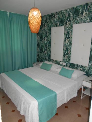 a bedroom with a large white bed with green curtains at Beach Boys Resort Men Only solo hombres in Maspalomas
