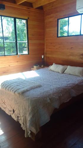 a bedroom with a bed in a room with windows at La casita del bosque in Punta Indio