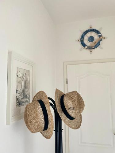 two straw hats on a lamp in a room with a clock at Olea Mar apartma in Pobegi