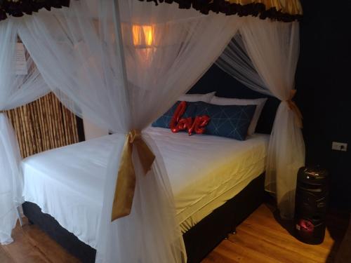 a bedroom with a canopy bed with white curtains at Cabaña Macareo in Tuluá