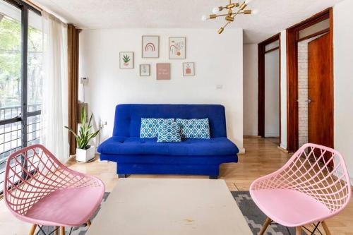a living room with a blue couch and two pink chairs at Park Narvarte in Mexico City
