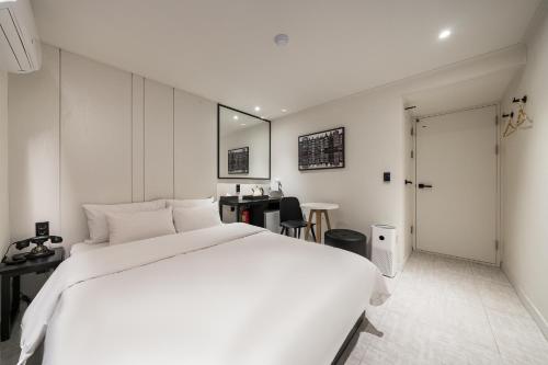 a bedroom with a large white bed and a table at Greaten Hotel in Seoul