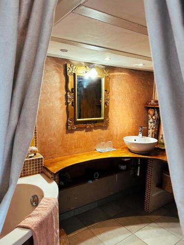 une salle de bain avec un lavabo, une baignoire et un miroir dans l'établissement Casaluna, chambre climatisée dans maison de village, à Sotta