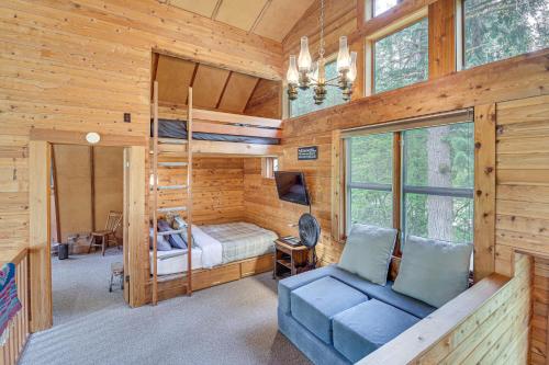 Dormitorio en cabaña de madera con litera y sofá azul en Riverfront Skykomish Cabin with Private Hot Tub!, en Skykomish