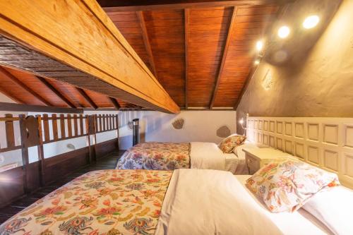 a bedroom with two beds and a wooden ceiling at Finca Casas Nanitas in Moya