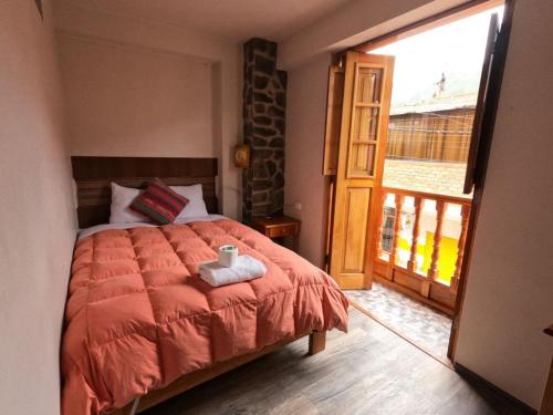 1 dormitorio con 1 cama y puerta a un balcón en hostal Balcon de Piedra, en Urubamba