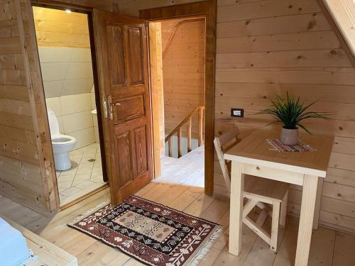 a room with a toilet and a table and a door at Guesthouse "Gjin Thana" in Theth