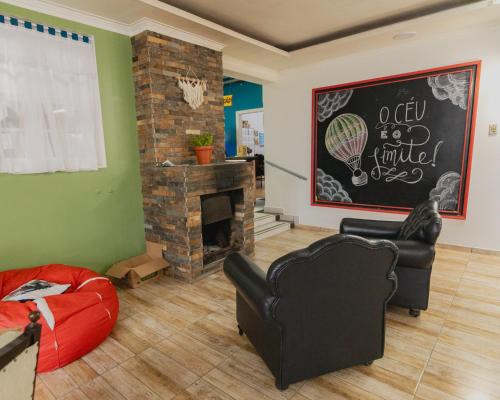 Araucária Hostel e Pousada في ساو بينتو دو سول: غرفة معيشة مع كرسيين ومدفأة