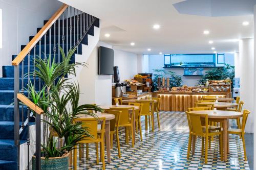 a restaurant with yellow chairs and tables and a staircase at Hotel Camino de la Sal in Zipaquir&aacute;