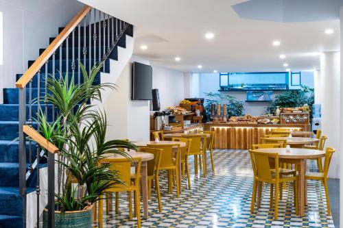 a restaurant with yellow chairs and tables and a staircase at Hotel Camino de la Sal in Zipaquirá