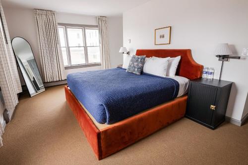 een slaapkamer met een groot bed en een blauwe deken bij The Farmhouse at Wylder Windham in Windham
