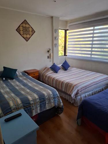 Habitación de hotel con 2 camas y ventana en Alojamiento Céntrico 24 hrs. con estacionamiento en Chillán