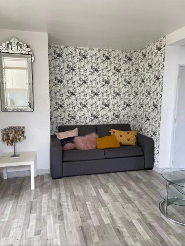 ein Wohnzimmer mit einem Sofa und einer Wand in der Unterkunft Proche centre T2 avec Terrasse in Biarritz