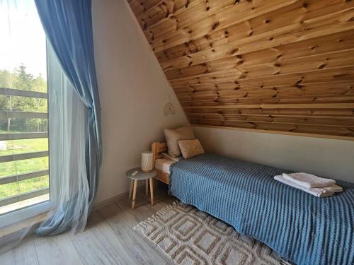 a bedroom with a bed and a large window at SierPlejs Hill - domek przy szlaku w Górach Sowich in Sierpnica