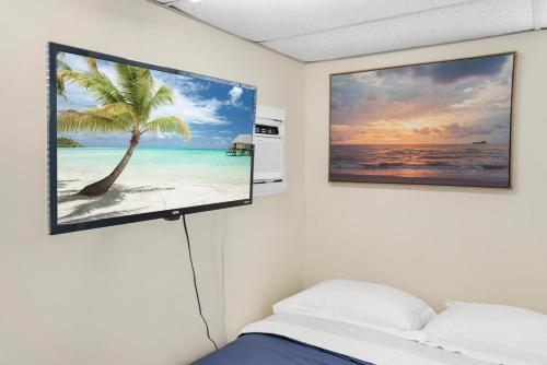 a tv hanging on a wall next to a bed at Private rooms in West Palm Beach - Close to Beaches in West Palm Beach