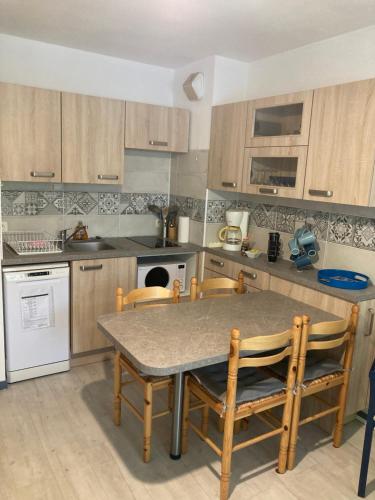 une cuisine avec une table et des chaises. dans l'établissement Appartement plage sables blancs, à Douarnenez