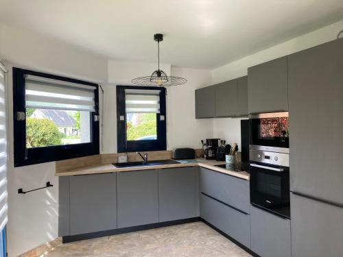 une cuisine avec des armoires blanches et des appareils noirs dans l'établissement La Bigorne, à Fouesnant