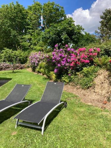 deux chaises longues sur l'herbe dans un jardin fleuri dans l'établissement La Bigorne, à Fouesnant