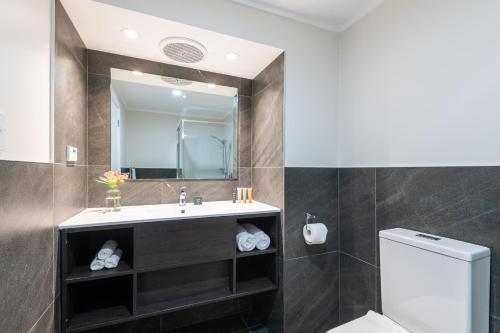 a bathroom with a sink and a toilet and a mirror at Marsden Stay Rotorua in Rotorua
