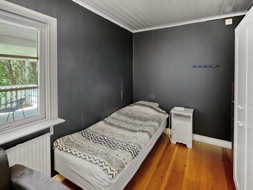a small bedroom with a bed and a window at Spacious Cabin for Work Crews, 10 Beds! in Ingelstad