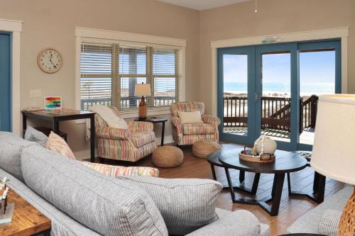 a living room with a couch and chairs and a balcony at The Blue Turtle by Pristine Properties Vacation Rentals in Mexico Beach