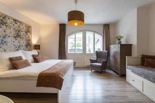 a bedroom with a bed and a chair and a window at Wellness Pension Fulda Černý Důl in Cerny Dul
