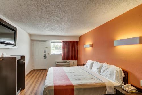 a bedroom with a large bed with an orange wall at Motel 6-Berea, KY in Berea