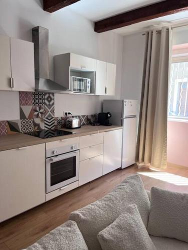 une cuisine avec des armoires blanches et un four à plaques de cuisson dans l'établissement Appartement grand confort 3 chambres avec cour intérieure, à Marseille