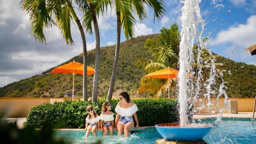a woman and two girls sitting next to a fountain at Scrub Island Resort, Spa & Marina in The Mill