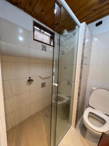 a bathroom with a toilet and a glass shower at Hospedagem Casa Maracujá in Trindade