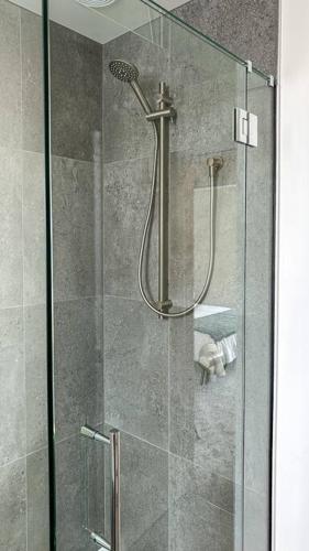 a shower stall with a glass door with a shower head at Hop, Skip, Jump to the city ! in Christchurch
