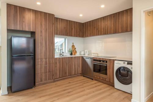 een keuken met houten kasten en een roestvrijstalen koelkast bij Hop, Skip, Jump to the city ! in Christchurch