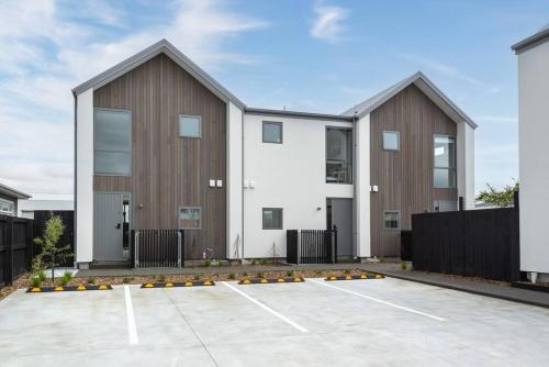 two buildings in a parking lot next to a fence at Hop, Skip, Jump to the city ! in Christchurch