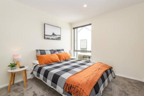 een slaapkamer met een bed met een oranje deken en een raam bij Hop, Skip, Jump to the city ! in Christchurch