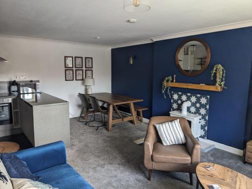 a living room with a blue wall and a table at Nautical nook, East Yorkshire two bed flat, free parking and WiFi in Hull
