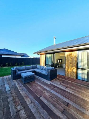 a patio with blue couches on a wooden deck at Spacious Family Home in Kirwee