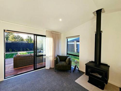 a living room with a wood stove and a chair at Spacious Family Home in Kirwee